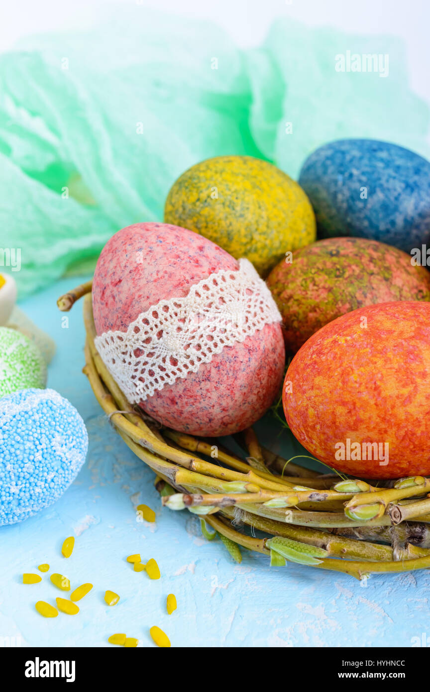 Colorful painted eggs in a nest of twigs of willow on a light ...