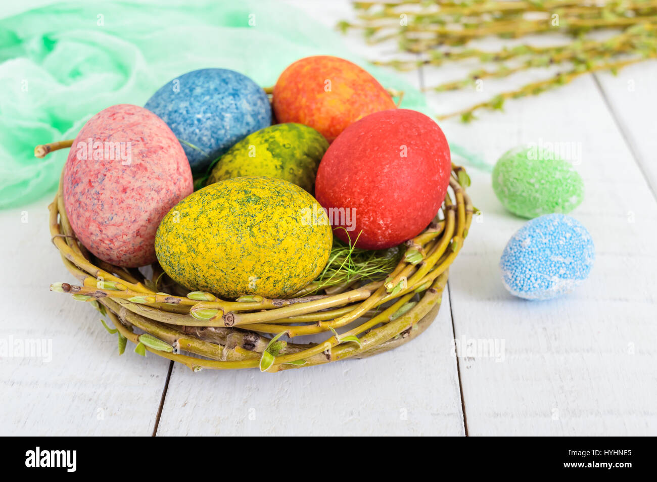 Colorful painted eggs in a nest of twigs of willow on a light ...