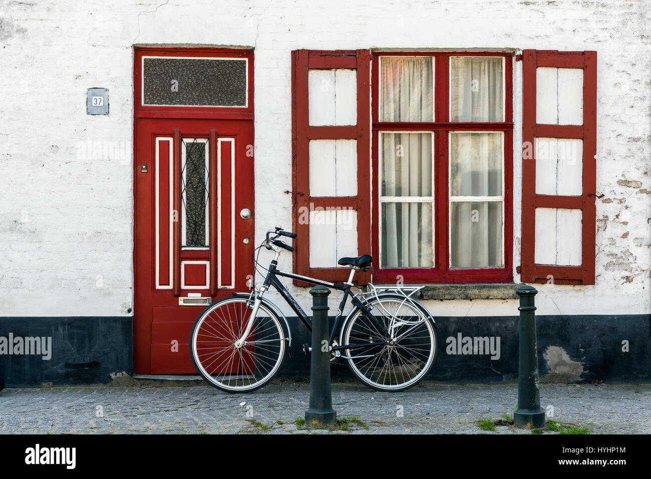 Bike parked against a door and window in Damme, West Flanders, Belgium Stock Photo