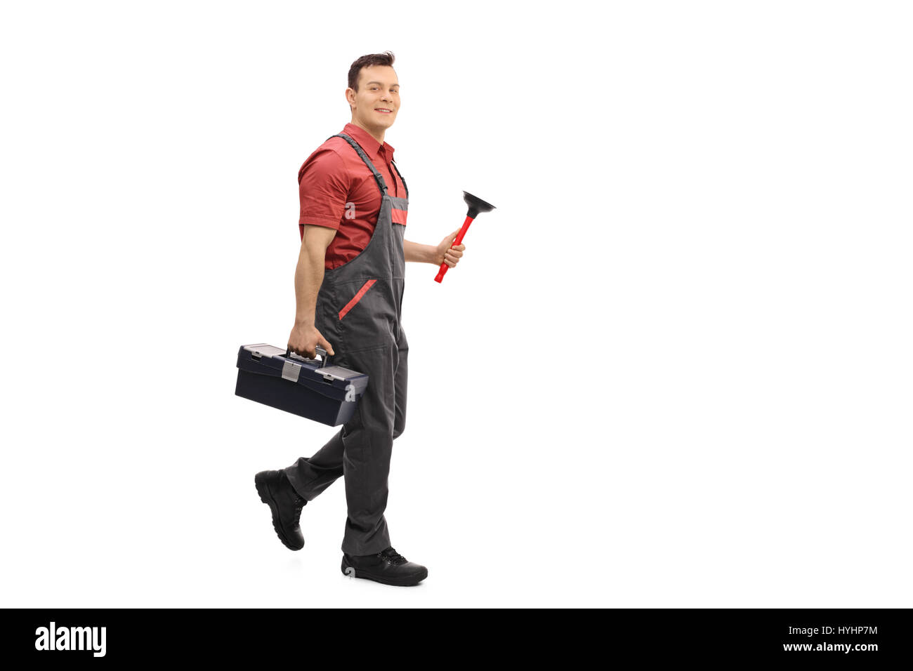 Full length portrait of a plumber with a toolbox and a plunger walking and looking at the camera isolated on white background Stock Photo