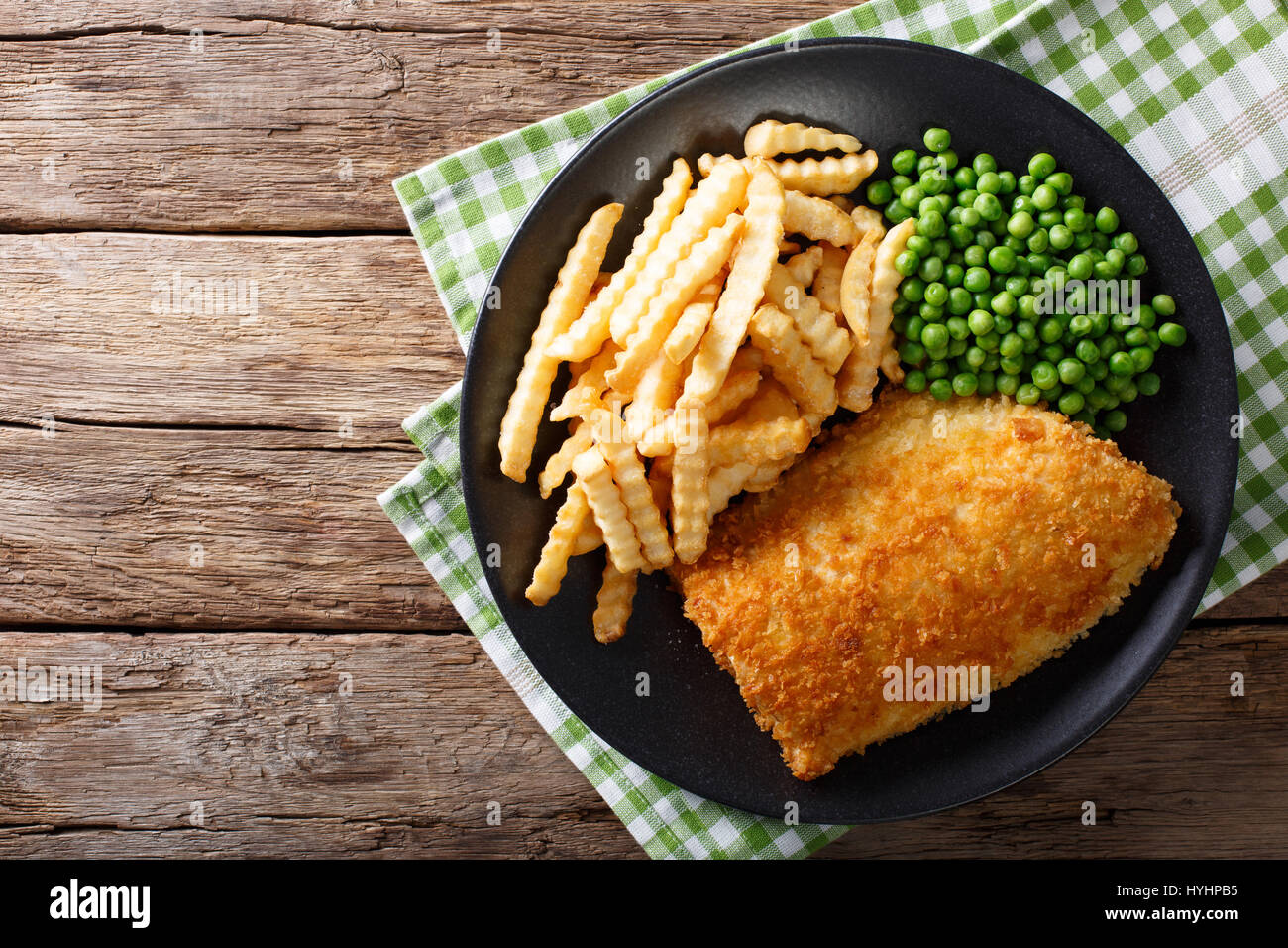 Traditional British food: Fish and chips with green peas close-up on a plate on a table. horizontal view from above Stock Photo