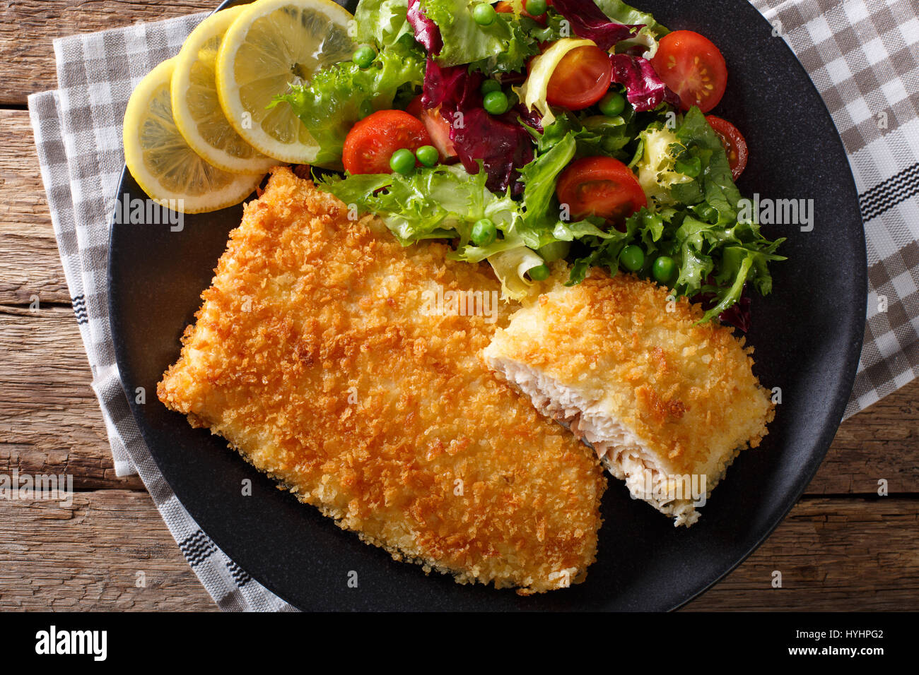 Fried fish fillet in breading and fresh vegetable salad closeup on a