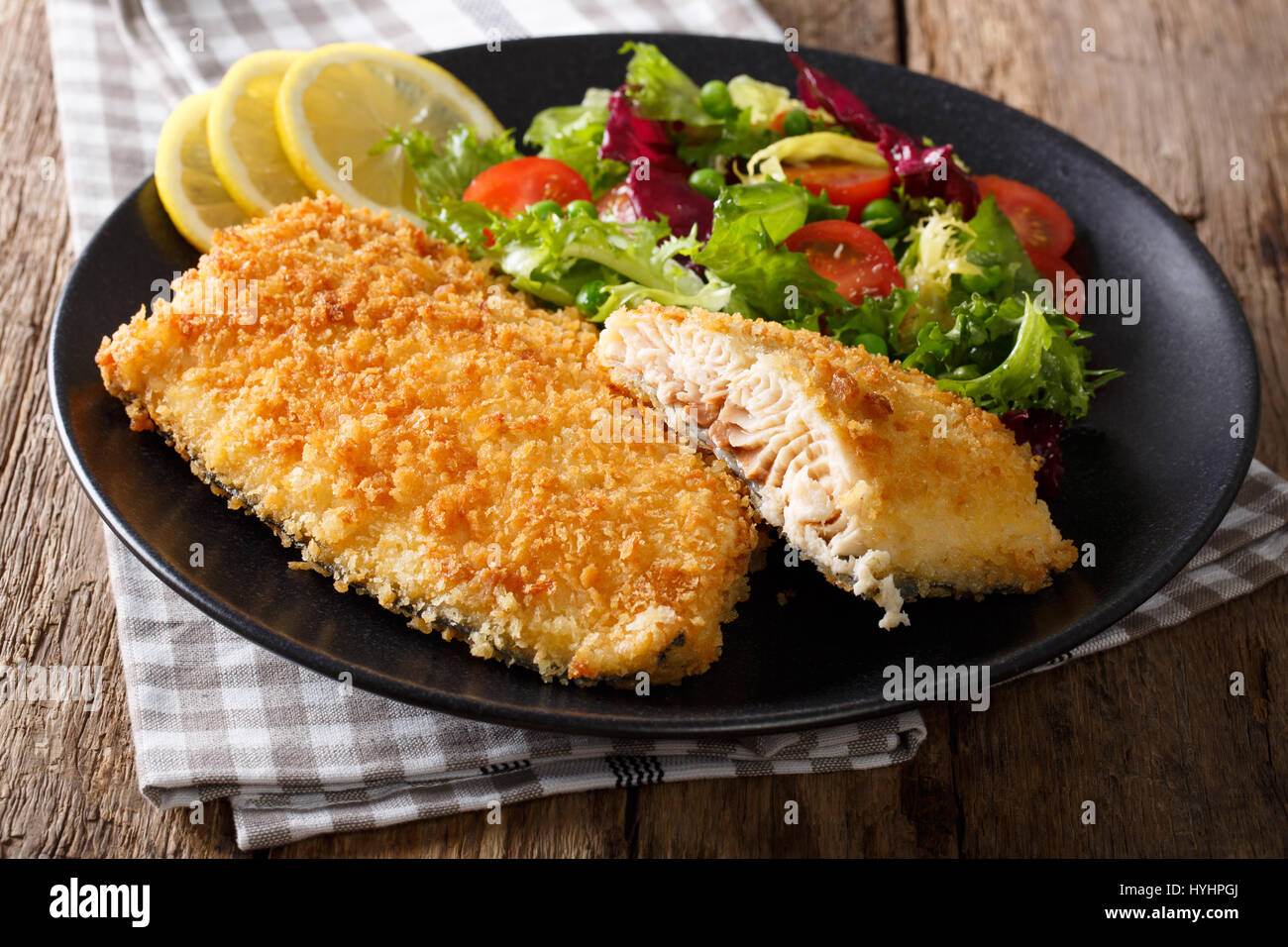 Tasty roasted Fish fillet in breadcrumbs and fresh vegetables closeup