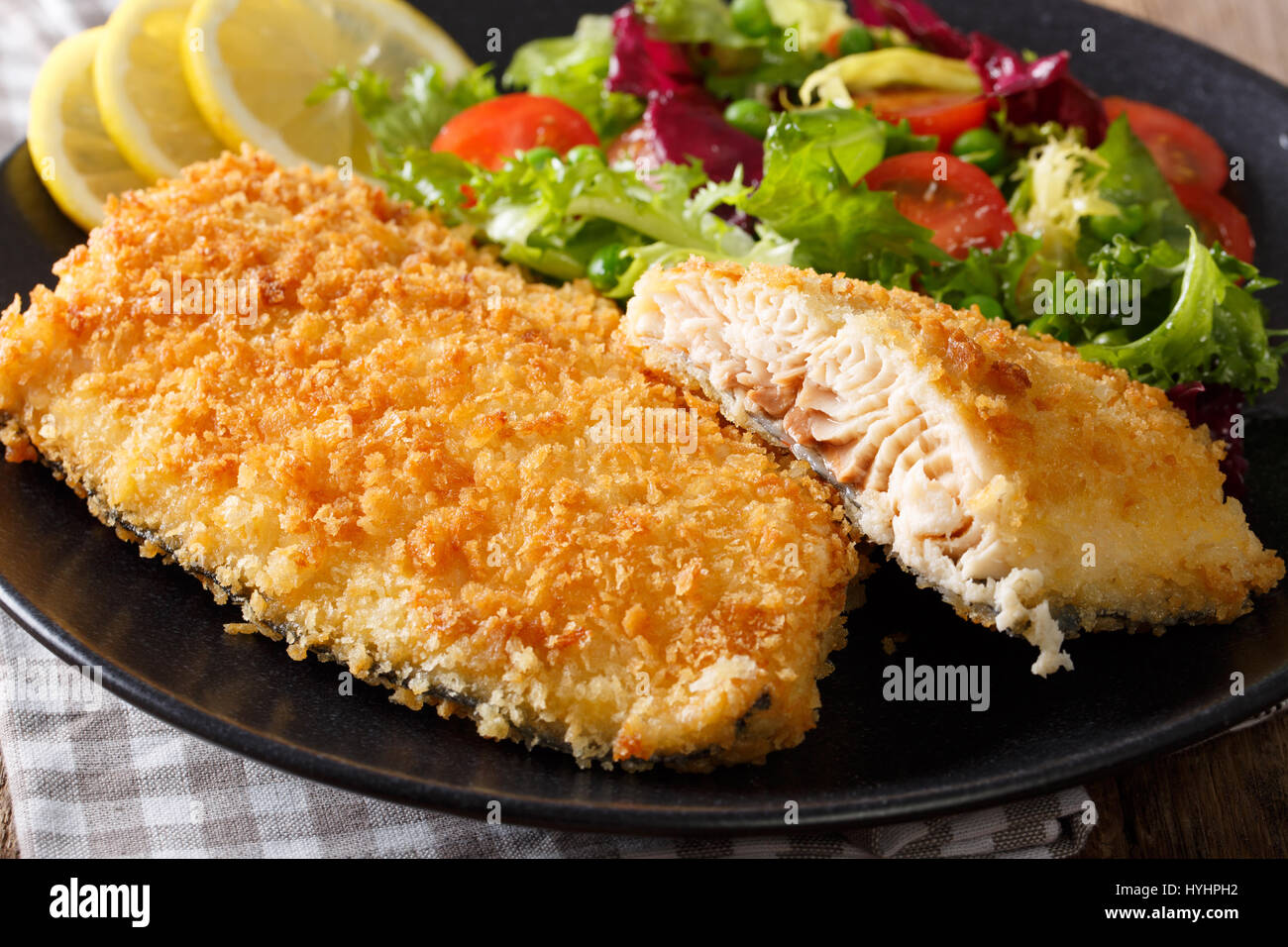 Fried Arctic char fish fillet in breadcrumbs and fresh vegetable salad closeup on a plate