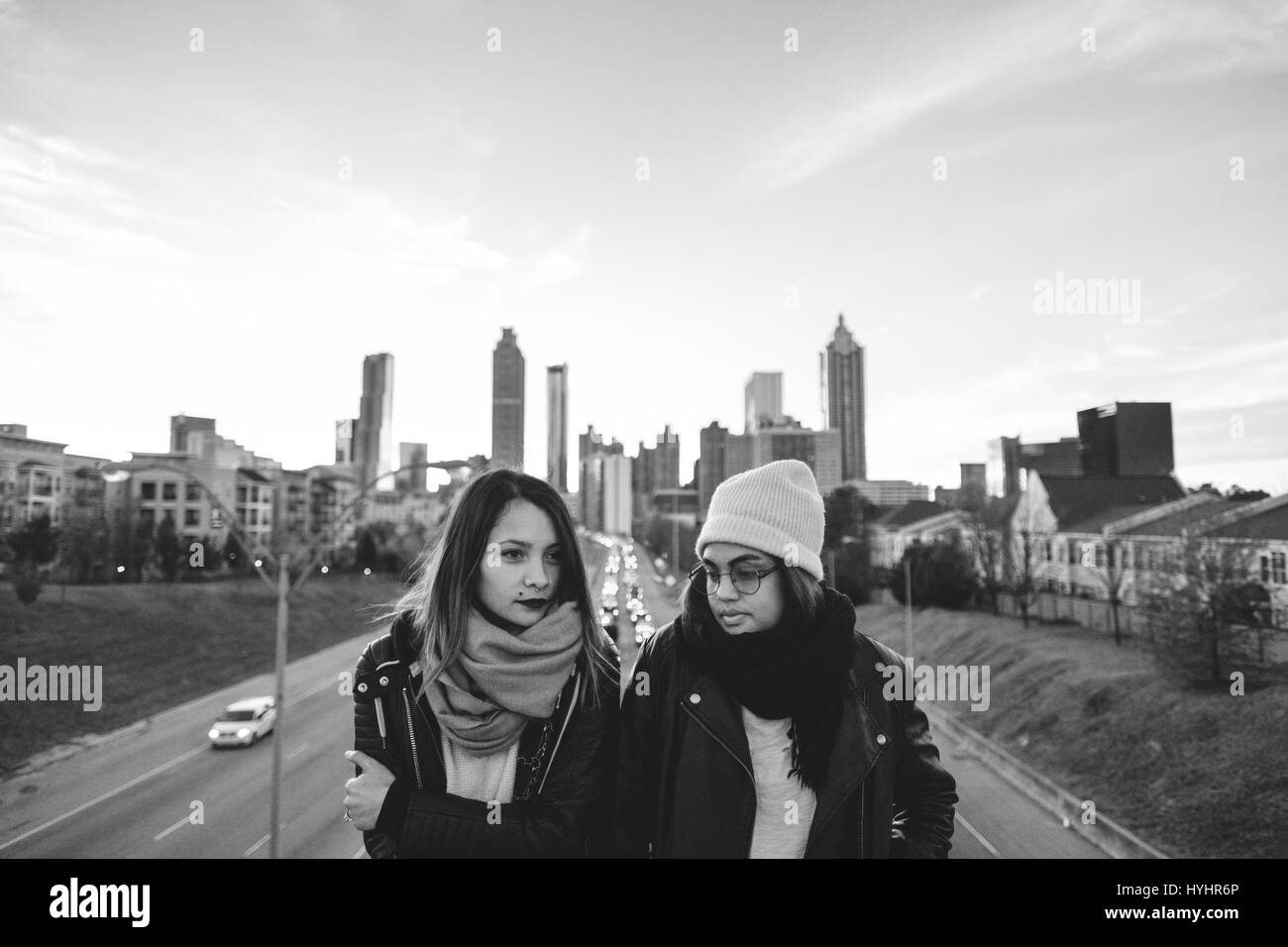 Young ethnic girls standing on bridge with city skyline in the background Stock Photo