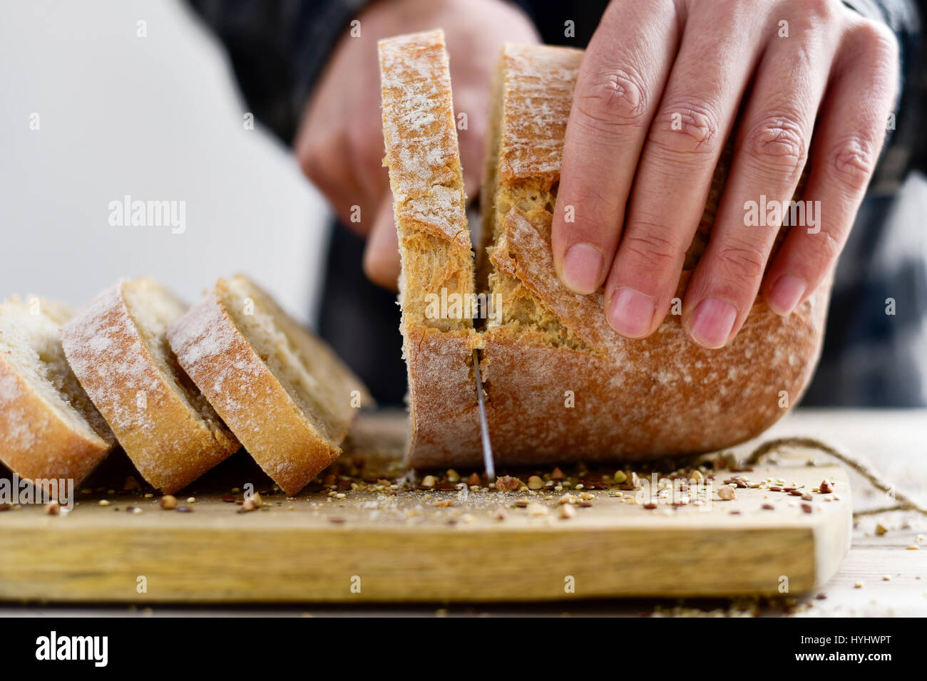 closeup of a young caucasian man cutting a loaf of bread in slices with