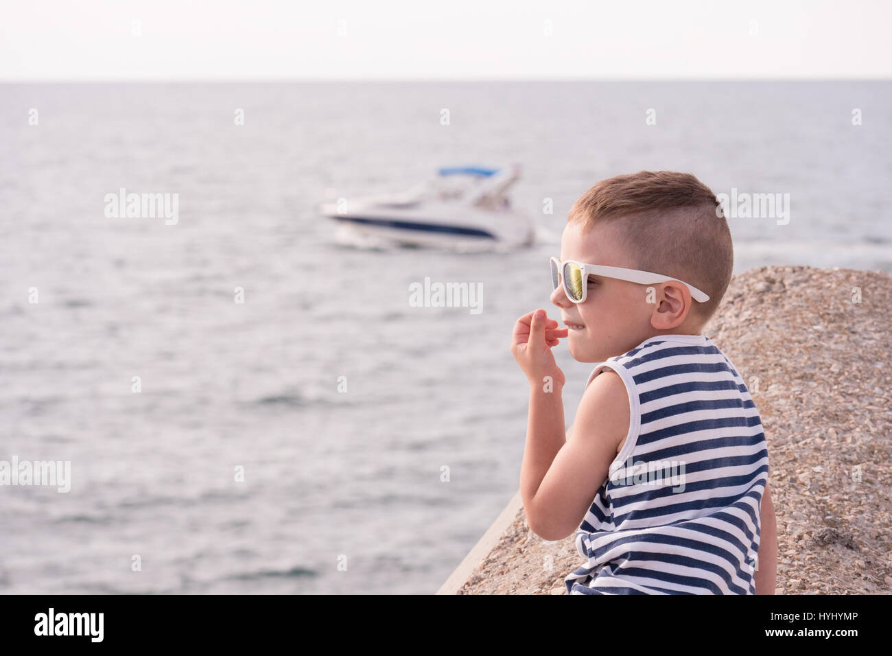 Beautiful little boy in sailor singlet and sunglasses on the background ...