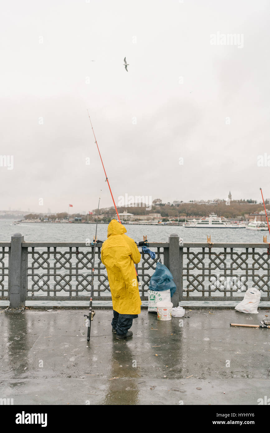 Man fishing off Galata bridge in the rain. Stock Photo