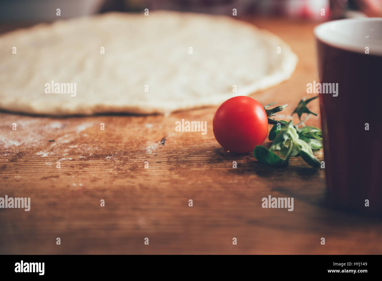 Pizza dough and cherry tomato on wooden table Stock Photo