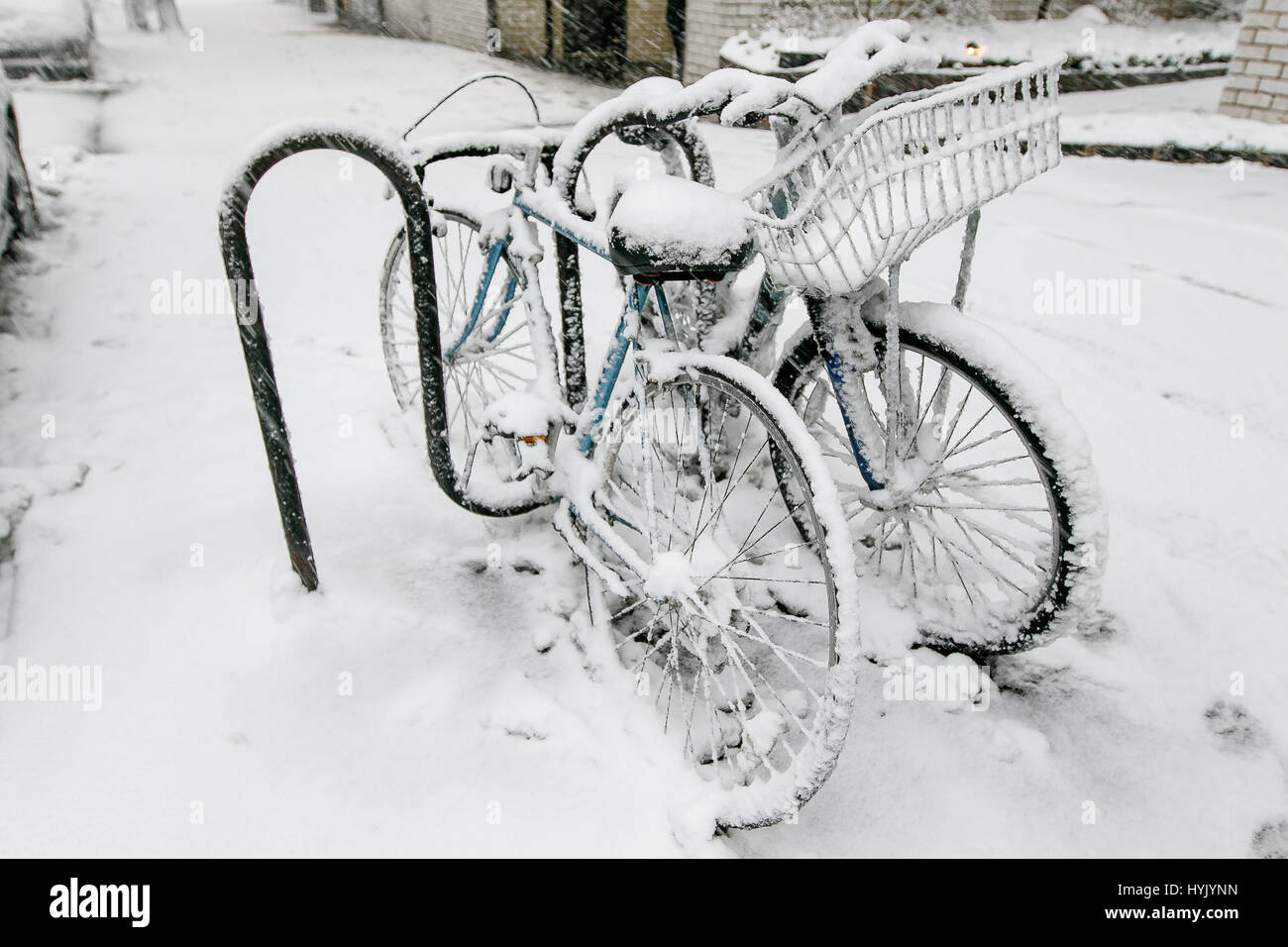 Two bicyles chained to a rack outside are covered in snow during a snowfall in Manhattan. Stock Photo