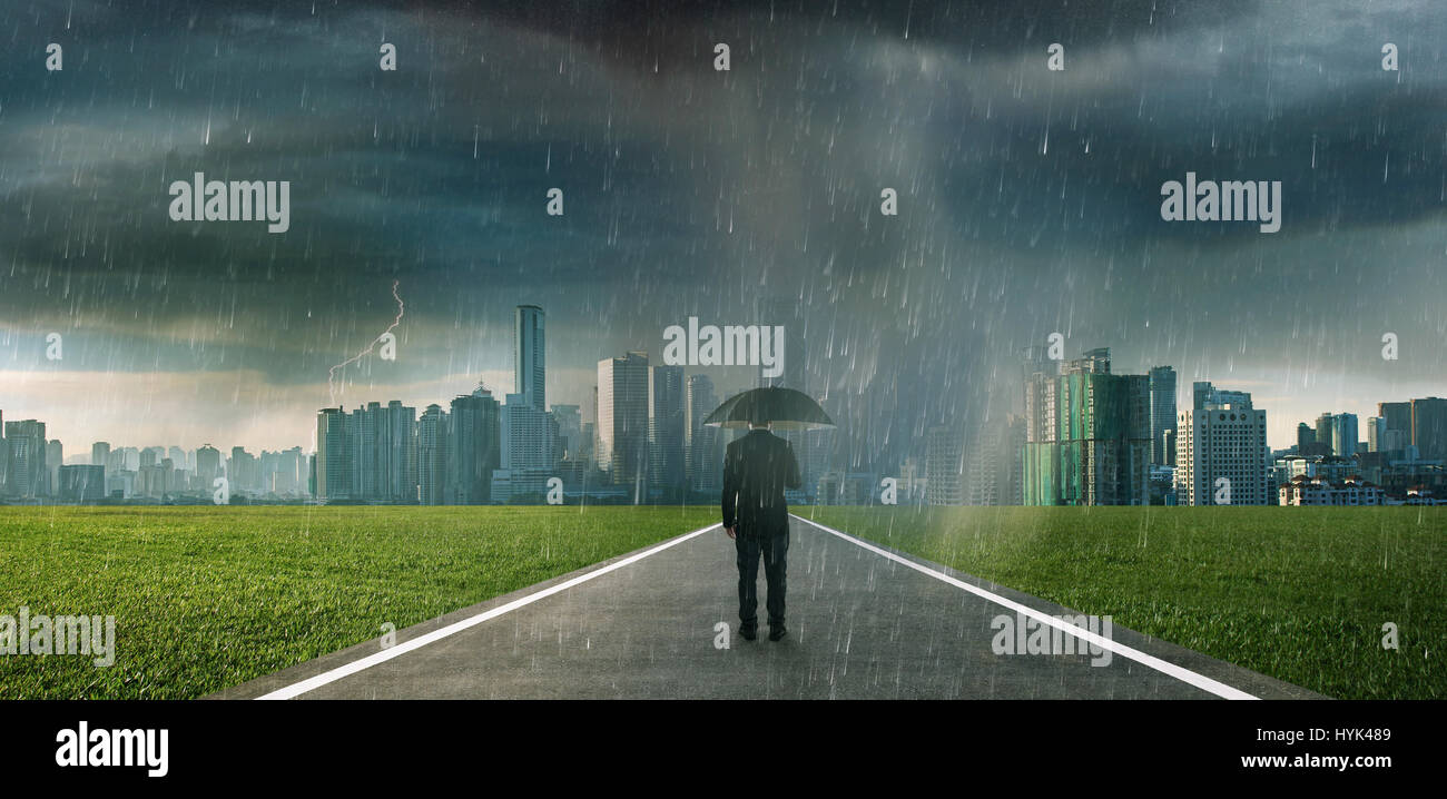 Businessman below storm rain with umbrella , risk and crisis concept . Stock Photo