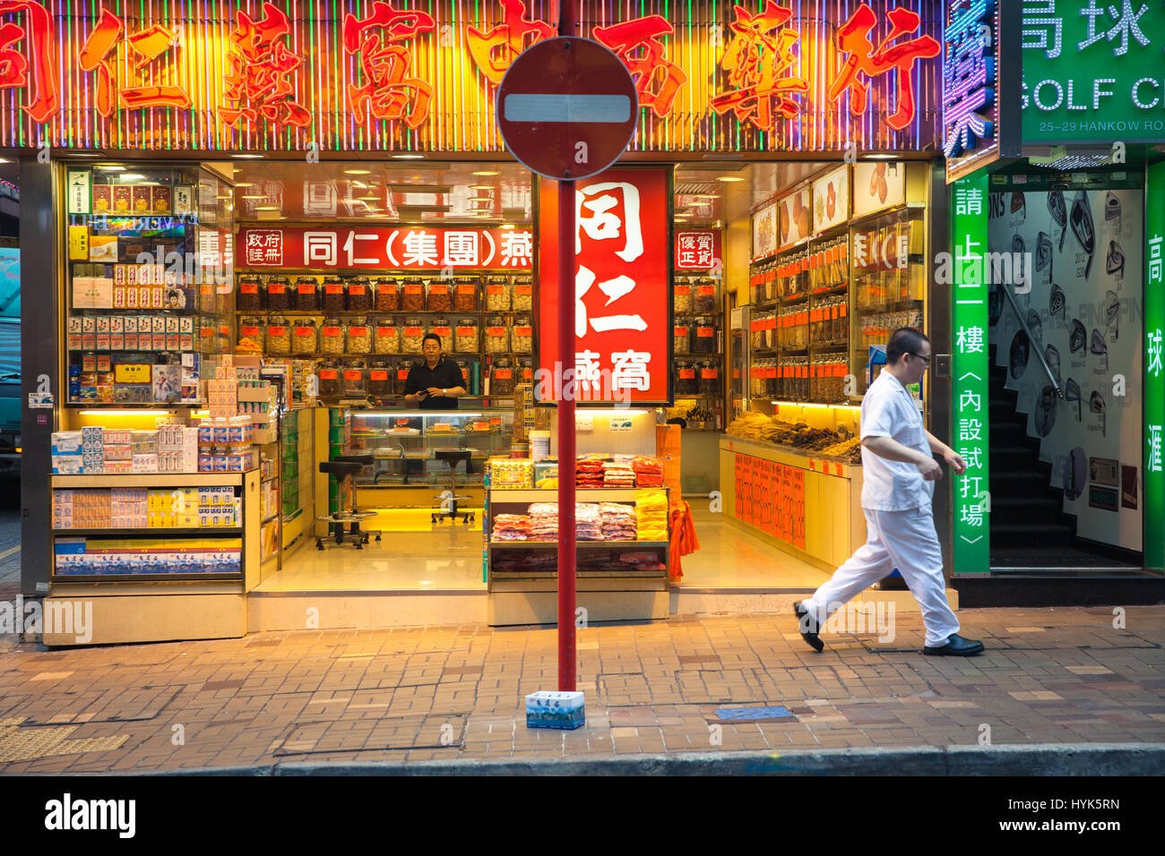 Hong Kong, China - February 16, 2014: Man passes by neon-lighted traditional Chinese medicine store on February 16, 2014 in Hong Kong, China. Stock Photo