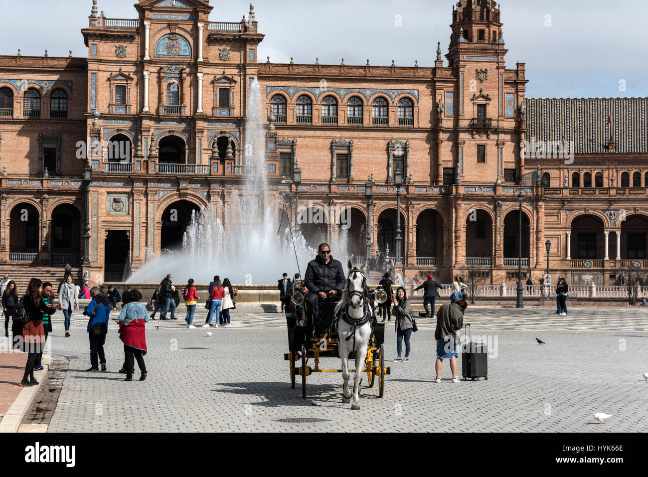 A horse & carriage giving tourist a guided tour at  the semi-circle frontage of the  Plaza de Espana, a popular venue in Seville, Spain.   The site is Stock Photo