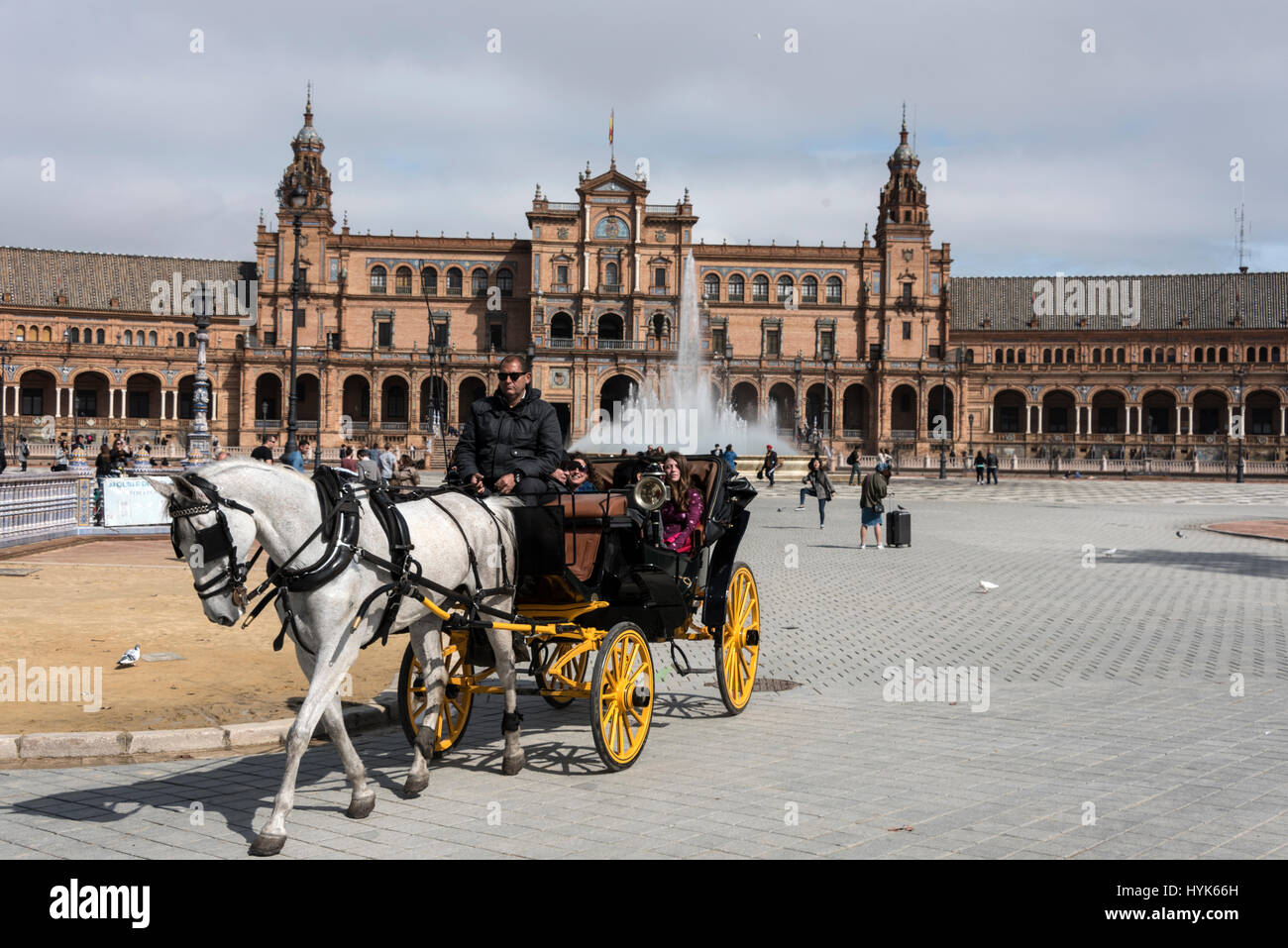 A horse & carriage giving tourist a guided tour at  the semi-circle frontage of the  Plaza de Espana, a popular venue in Seville, Spain.   The site is Stock Photo