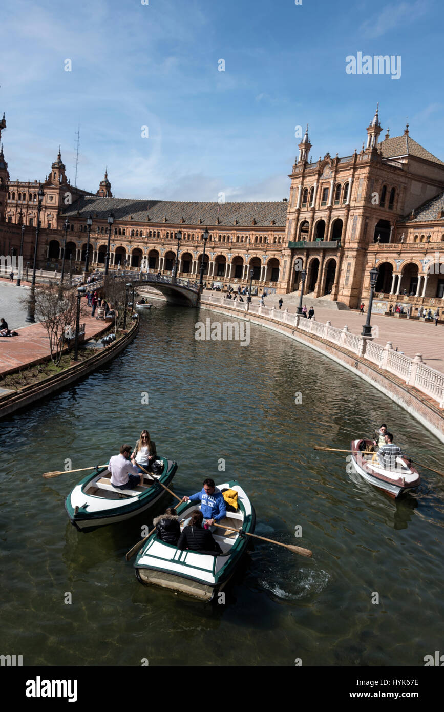 Visitors enjoying rowing small boats on a semi-circle moat with four small bridges at  the semi-circle frontage of the  Plaza de Espana, a popular ven Stock Photo
