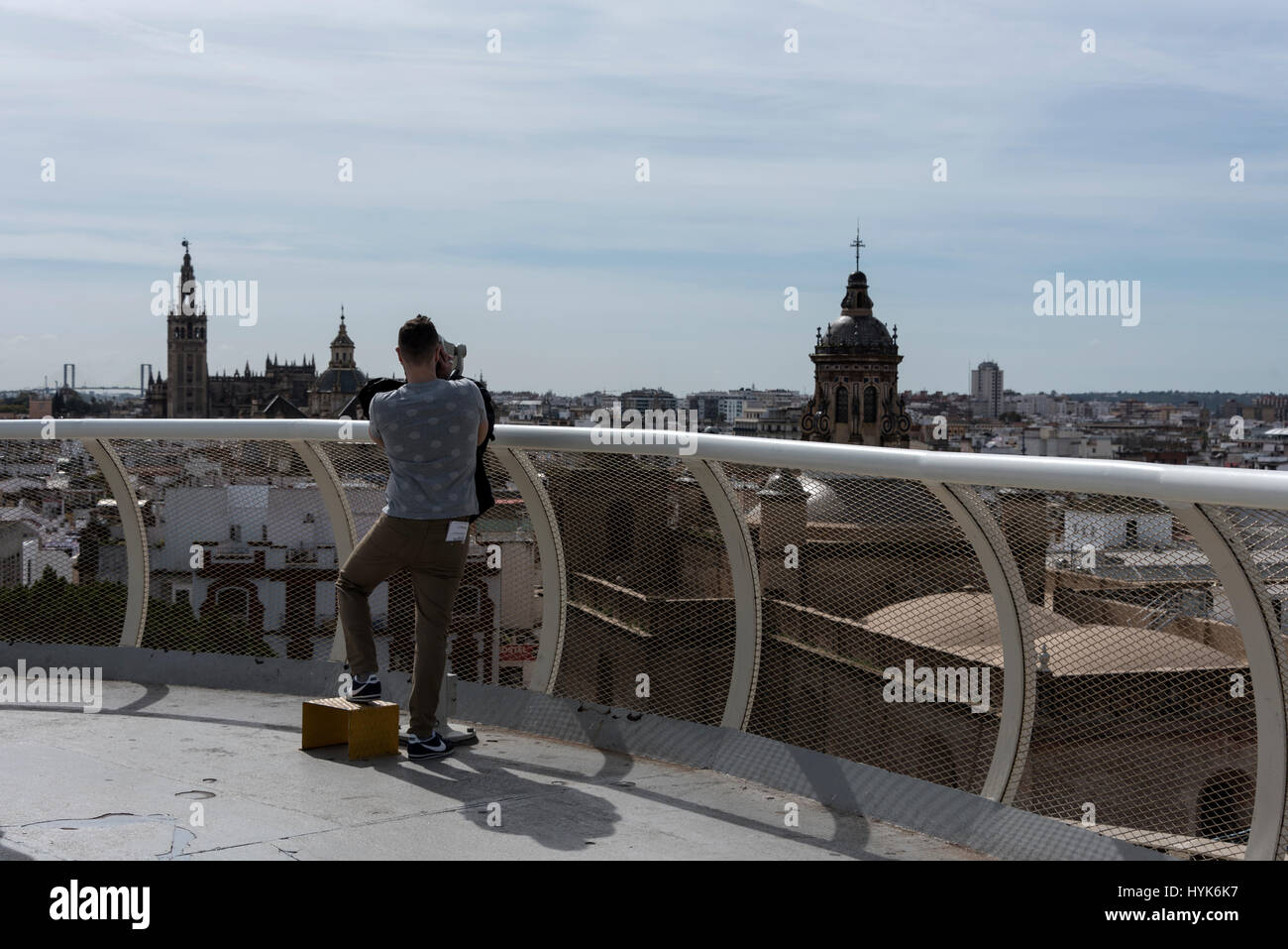 A young visitor looks through a telescope of the Seville skyline from the top of the Metropol Parasol, located at La Encarnacion Plaza (square) in the Stock Photo