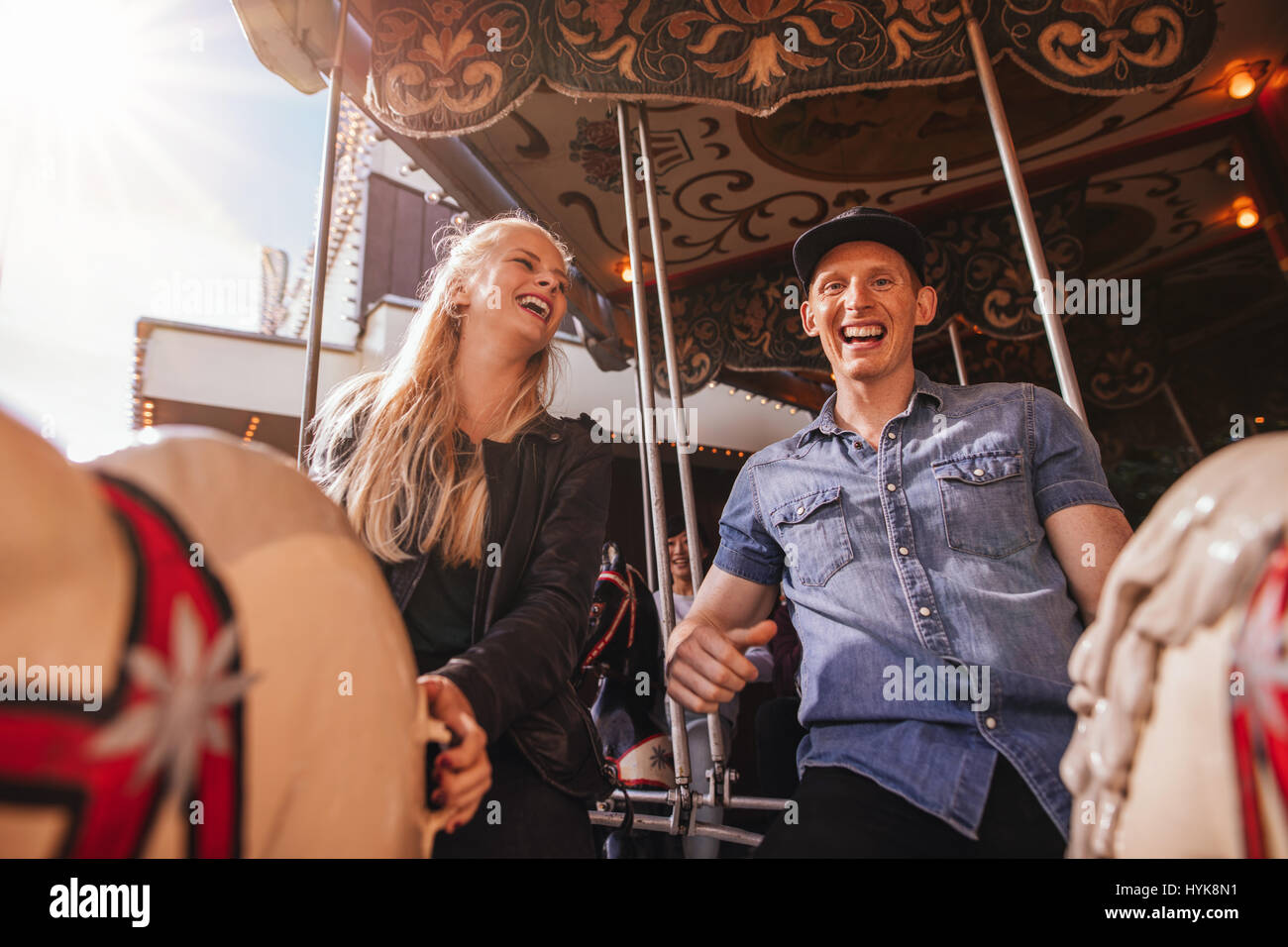 Smiling friends on amusement park carousel. Young couple on carousel ...
