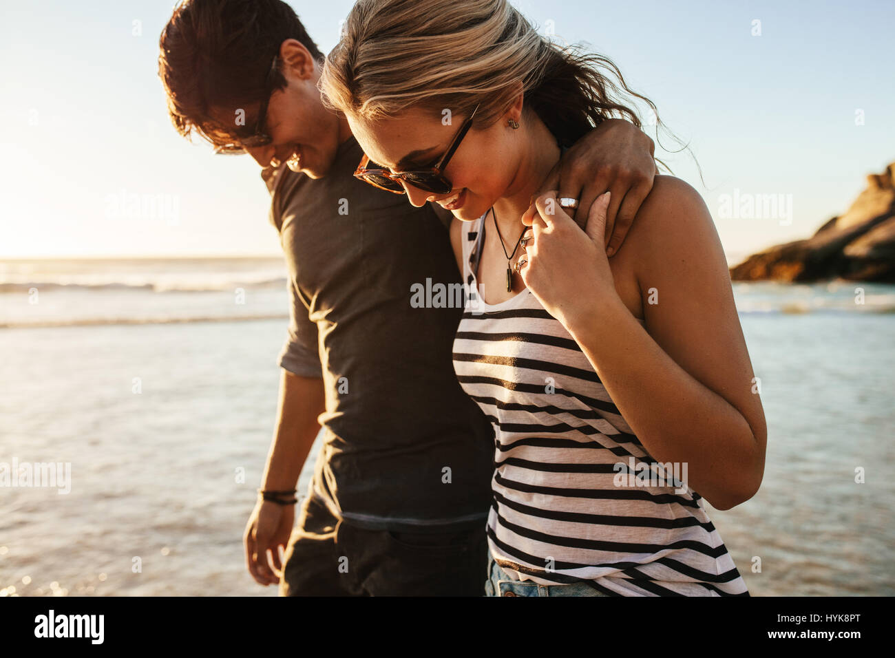 Portrait of happy young couple walking on sea shore. Man and woman on beach holiday. Stock Photo