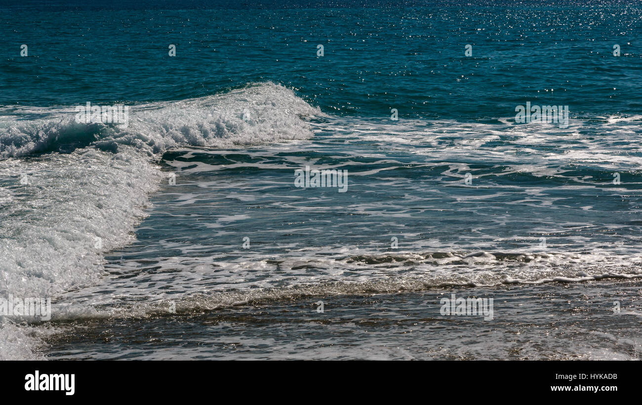 The surf of the blue turquoise sea with white perpendicular waves on the sandy beach. Kassandra,  Chalkidiki, Greece Stock Photo