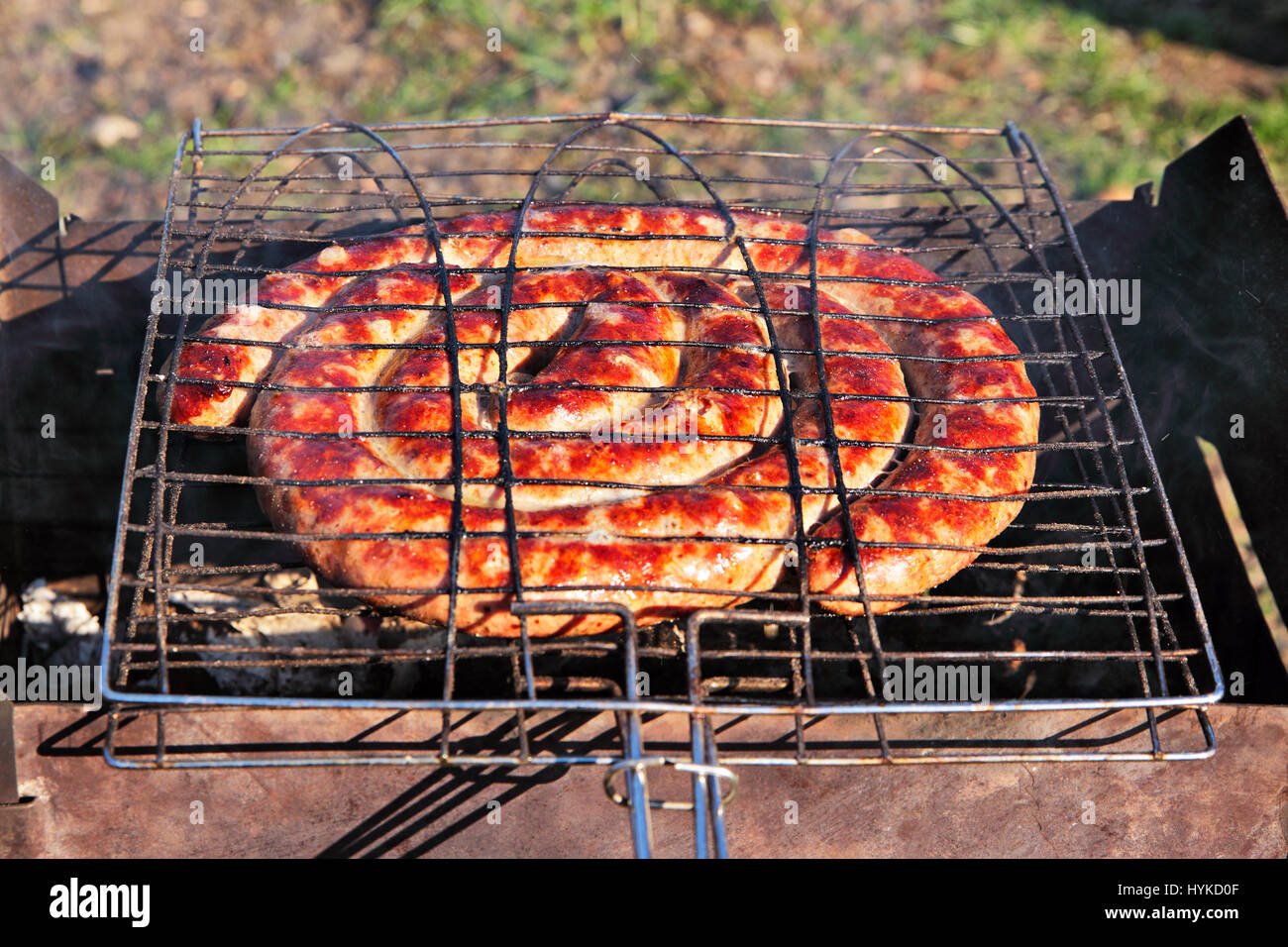 Beef sausages grilled on a coals. Outdoor kielbasa barbecue. BBQ on brazier. Stock Photo
