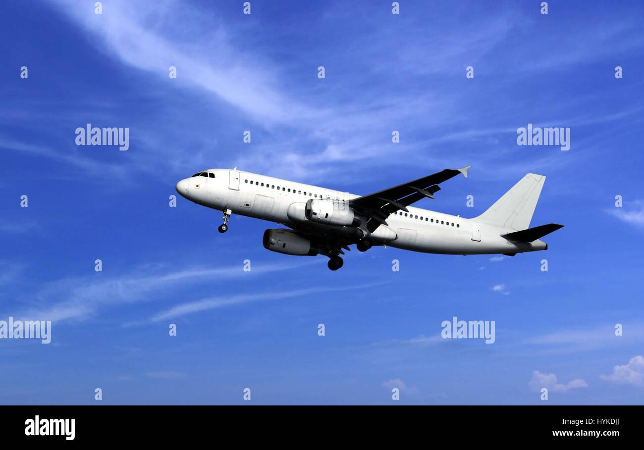 Passenger airplane take off under cloudy blue sky Stock Photo