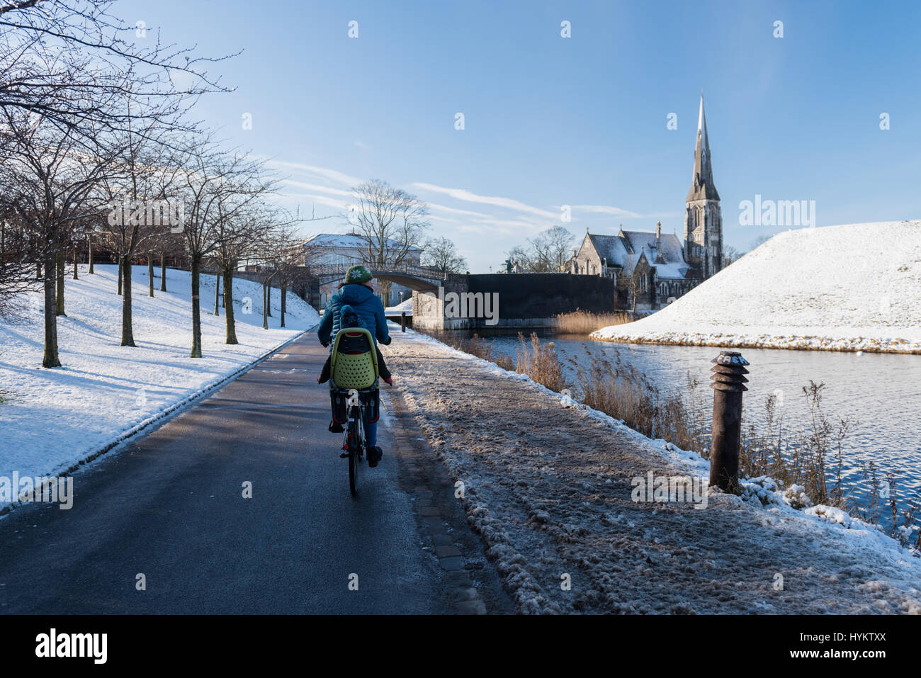 Mother cycling around Copenhagen with her son on the back of the bicycle exploring the city in the winter with snow on the ground Stock Photo