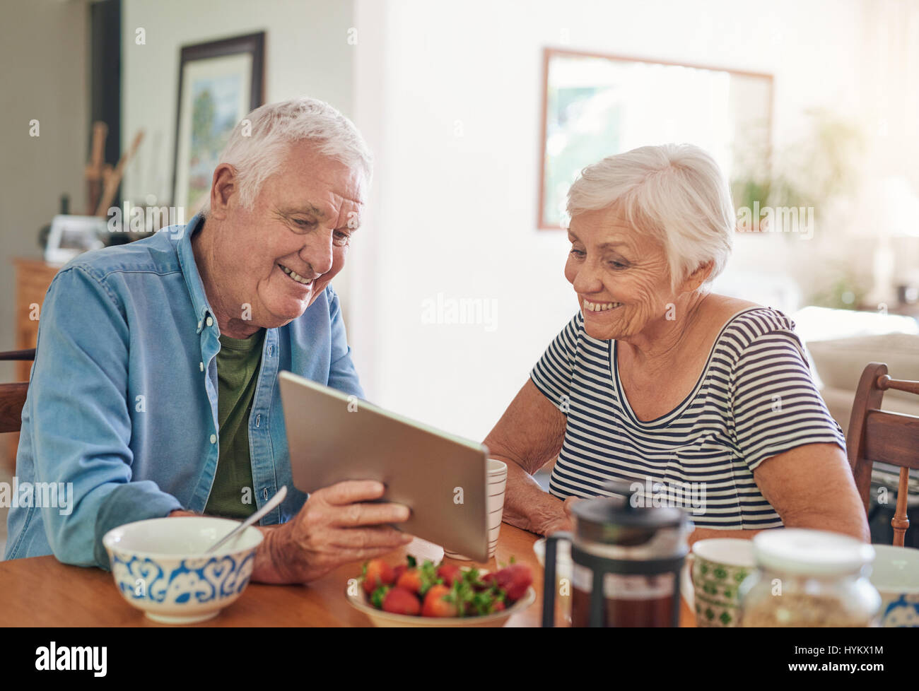 Smiling seniors using a digital tablet together over breakfast Stock Photo