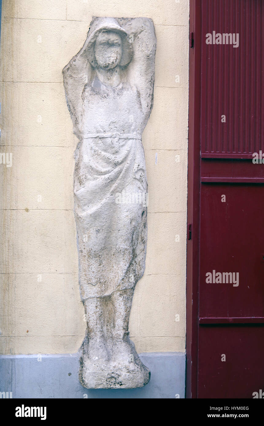 A presumably very old carved figure of a woman embedded in a wall in a shopping street in the centre of Nimes. Stock Photo