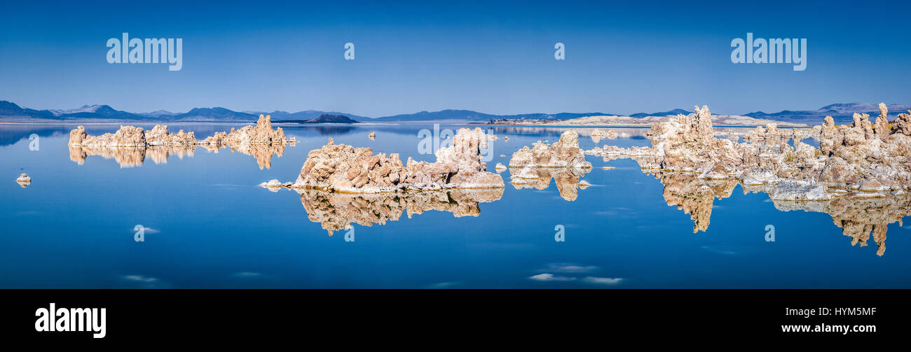 Panoramic view of fascinating tufa rock formations mirrored on calm water surface of famous Mono Lake on a beautiful sunny day with blue sky in summer Stock Photo