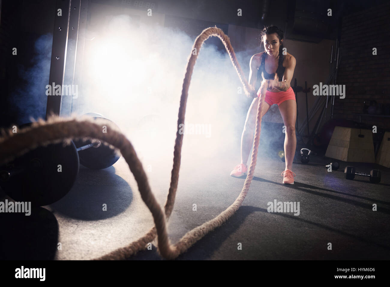 Determinated woman tossing ropes at gym Stock Photo