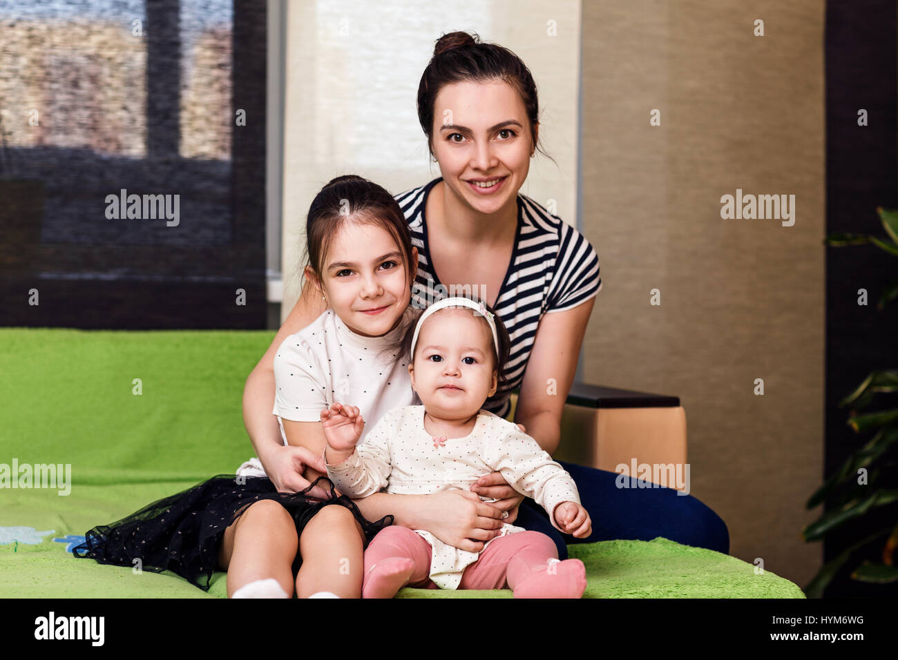 Mother and her daughters hugging and posing. Stock Photo