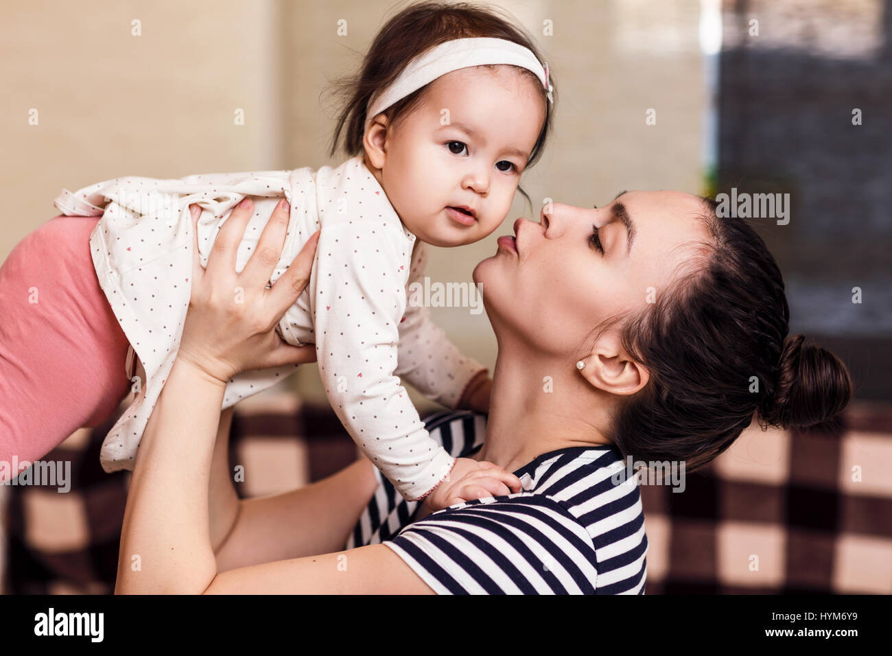 Young happy woman holding baby girl in hands. Stock Photo