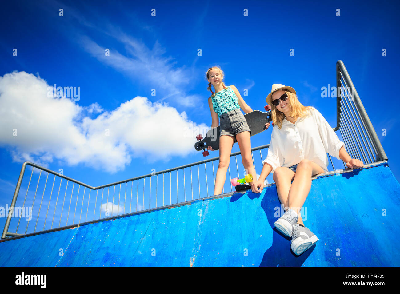 two teenage girls with a skateboard on halfpipe in the park Stock Photo