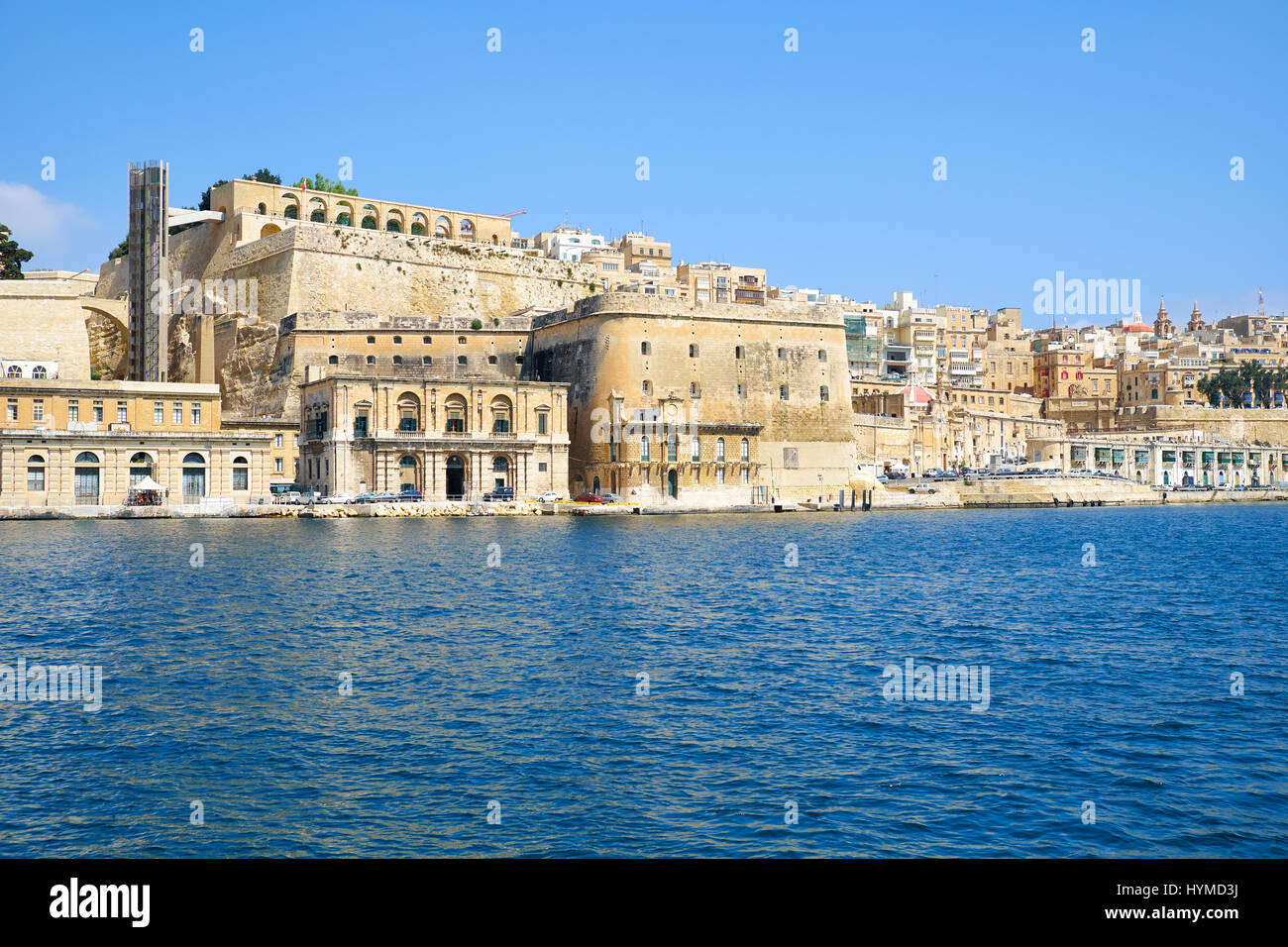 The view of Valletta capital city fortifications with Fort Lascaris and Upper and Lower Barrakka Gardens  from the water of Grand Harbour. Malta Stock Photo