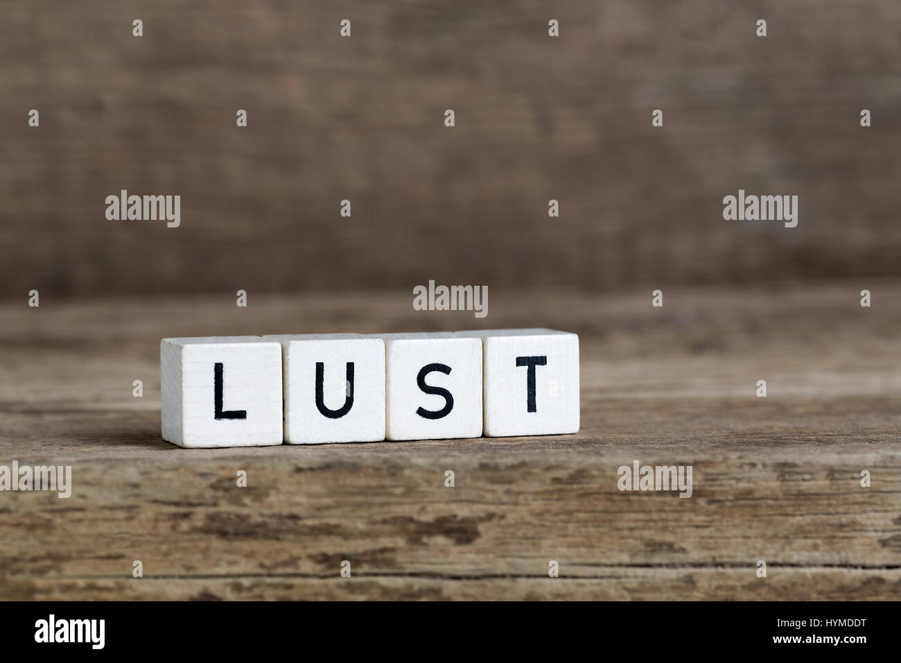 Lust, written in cubes on a wooden background Stock Photo