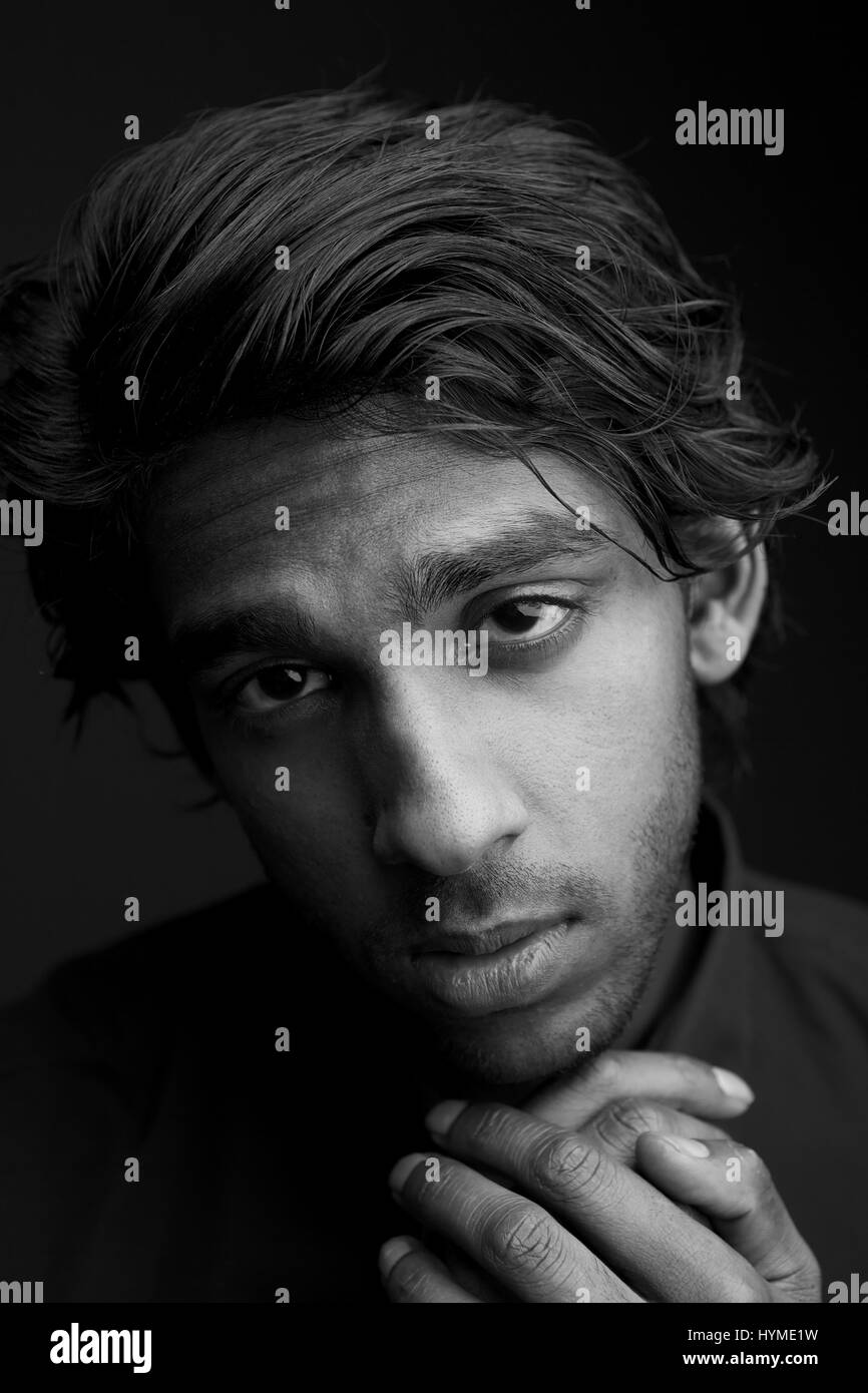 Close up black and white portrait of a young man with hand to chin ...