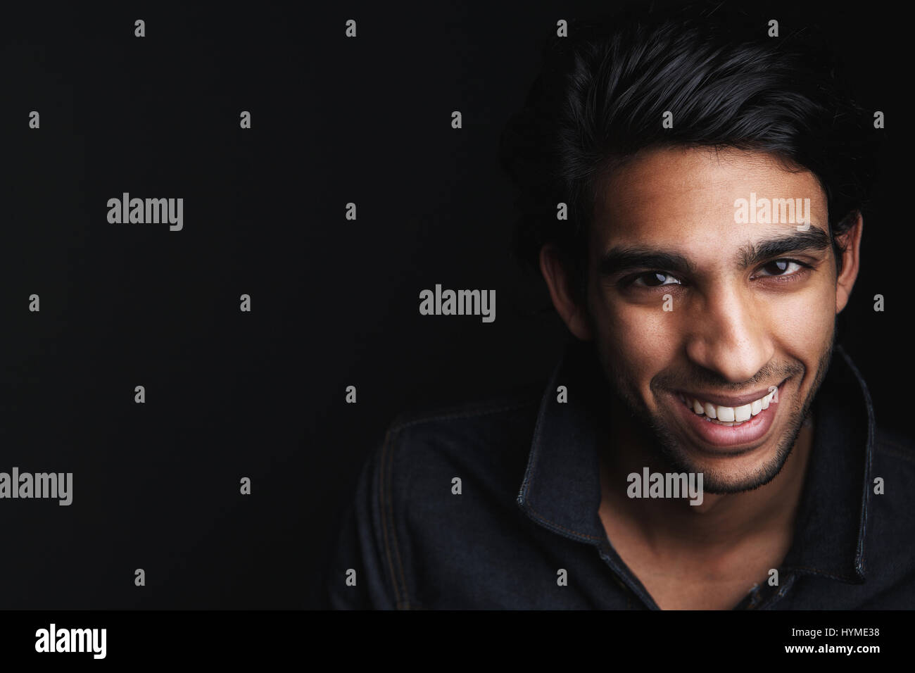 Close up portrait of a cheerful young man laughing on black background Stock Photo