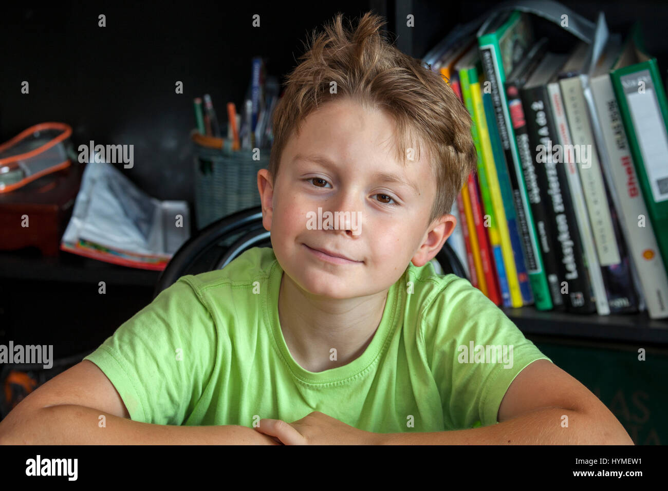 Portrait of a boy with a wry smile in front of the family library. Polish boy age 8. Zawady Central Poland Europe Stock Photo