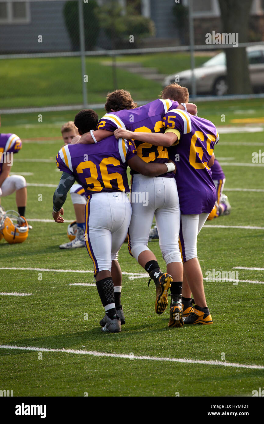 High school football players helping injured player off the field. Cretin-Derham Hall High School St Paul Minnesota MN USA Stock Photo
