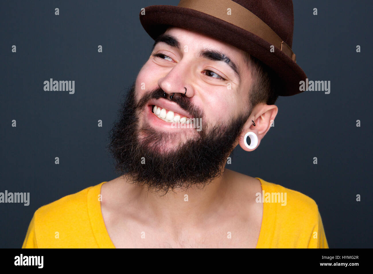 Close up portrait of a confident young man with beard smiling on gray ...