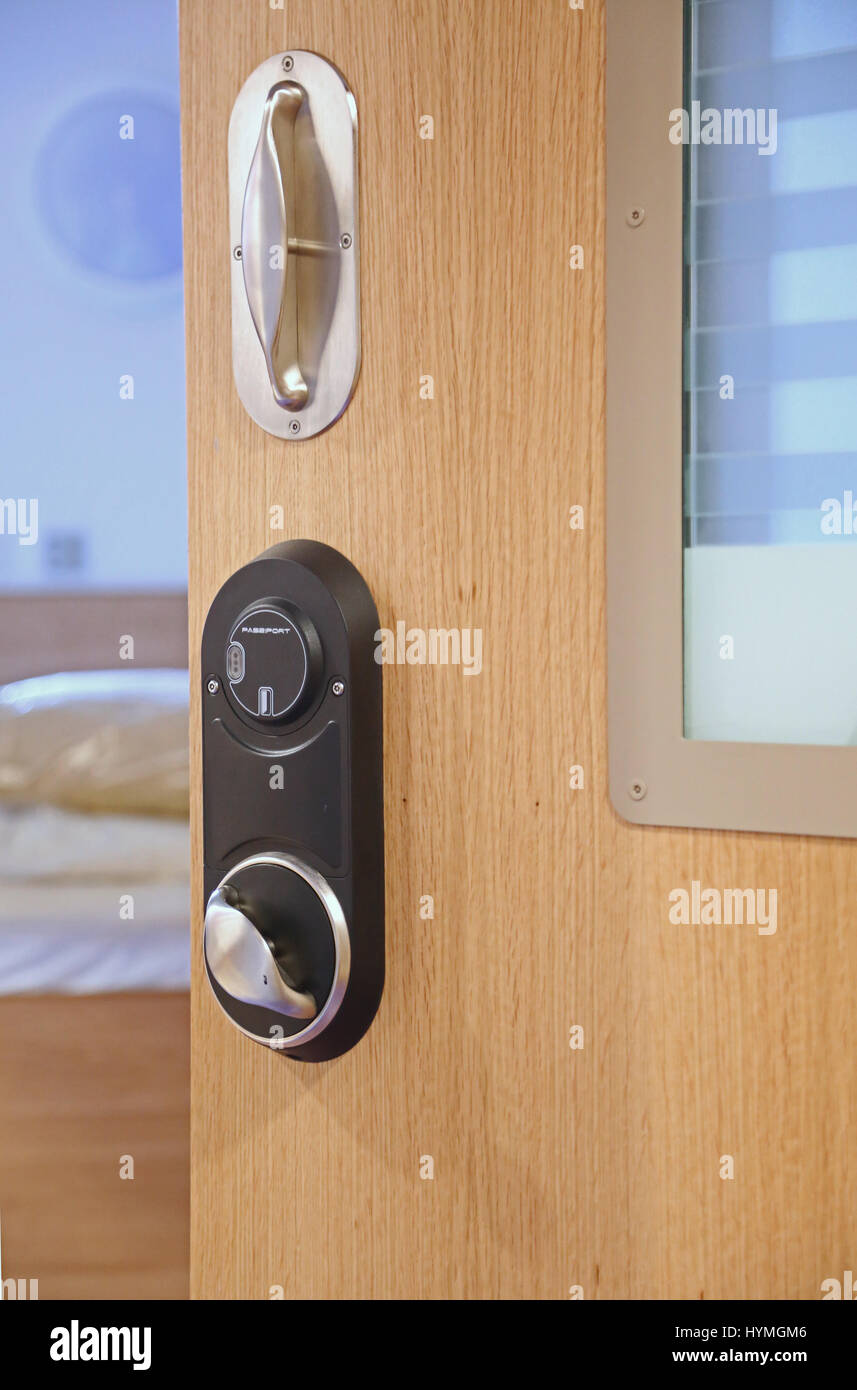 Close-up of a bedroom door in a secure, residential psychiatric unit. Shows anti-ligature door handle and electronic locking system. Stock Photo