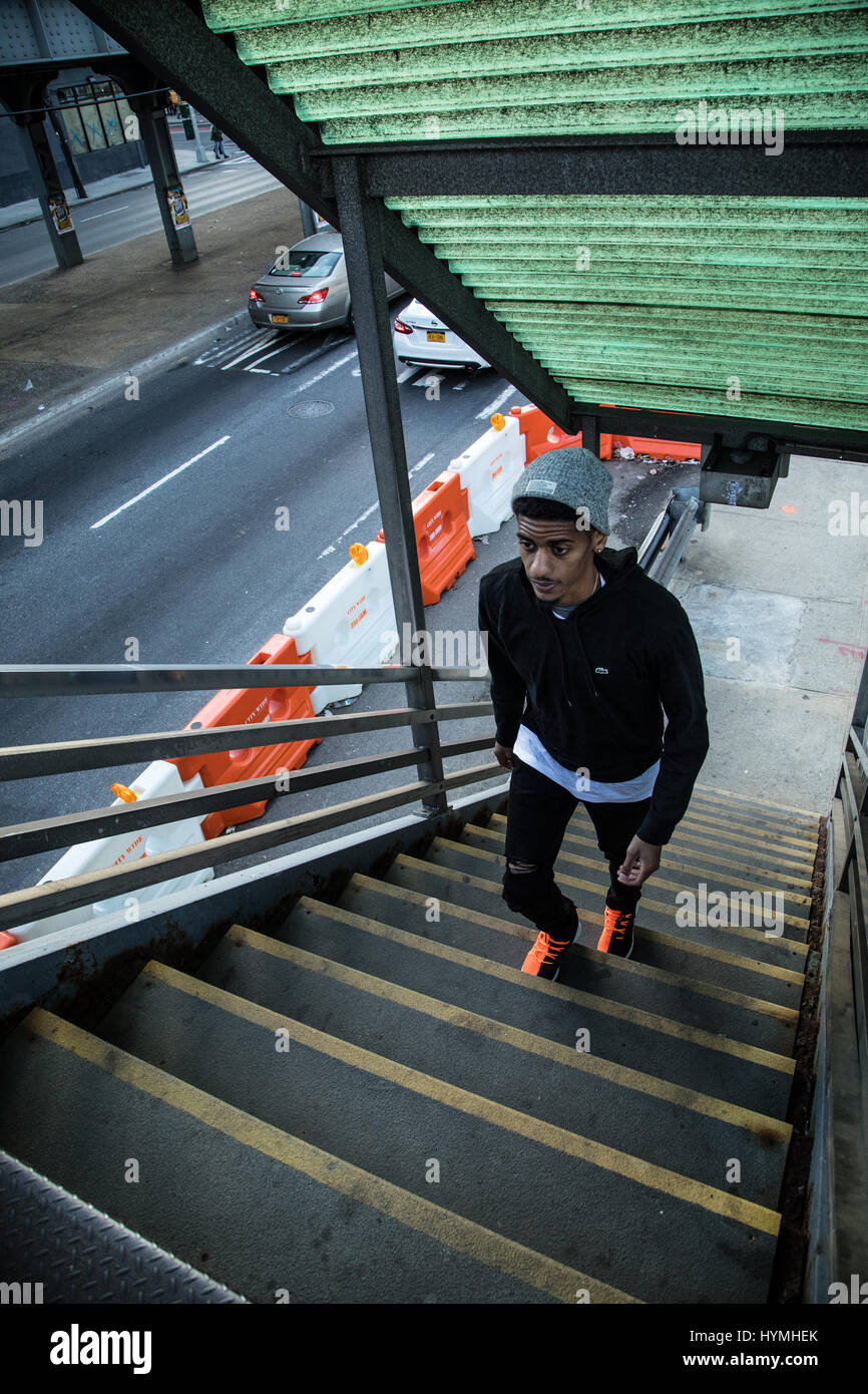 A candid portrait of a young hipster entering an above ground subway station in Brooklyn, New York City. Shot during the autumn of 2016. Stock Photo