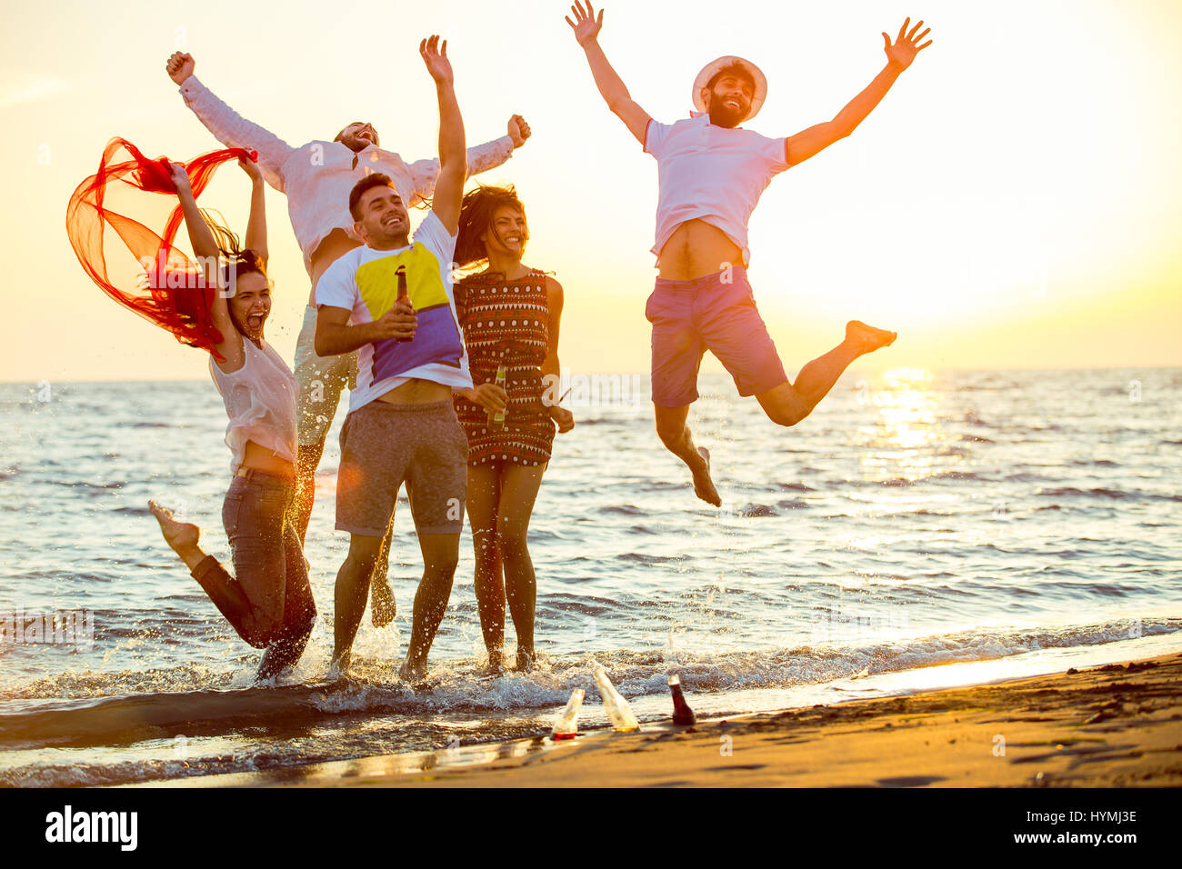 group of happy young people dancing at the beach on beautiful summer sunset Stock Photo