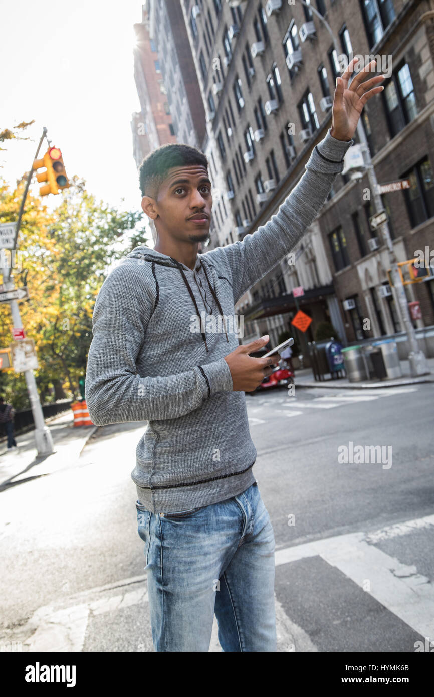 A young, hip, man hails a cab in New York City. Shot during the fall of 2016 in Manhattan. Stock Photo