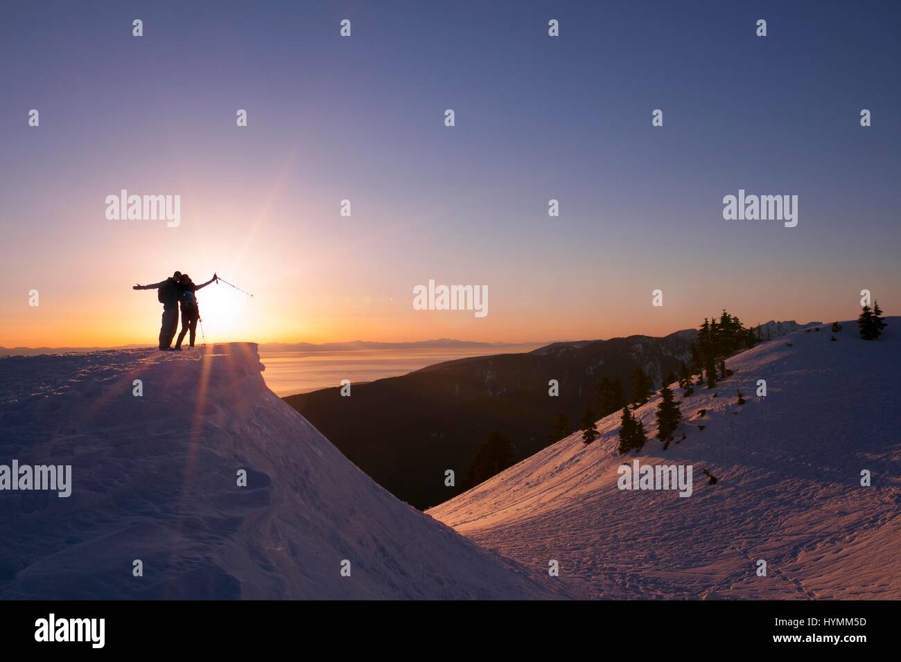 Silhouette of female hiker watching sunset in the background on Mount Seymour, Vancouver, British Columbia, Canada Stock Photo