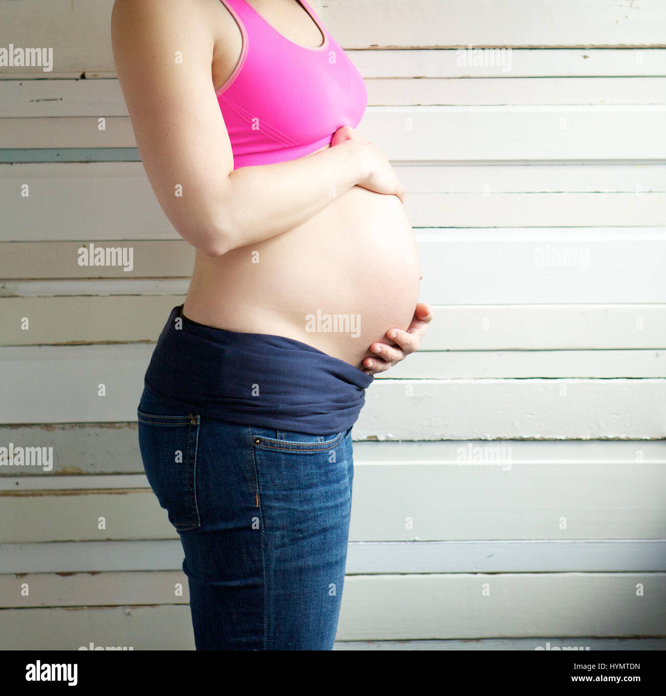 Close up portrait of a young pregnant woman holding stomach - side view ...