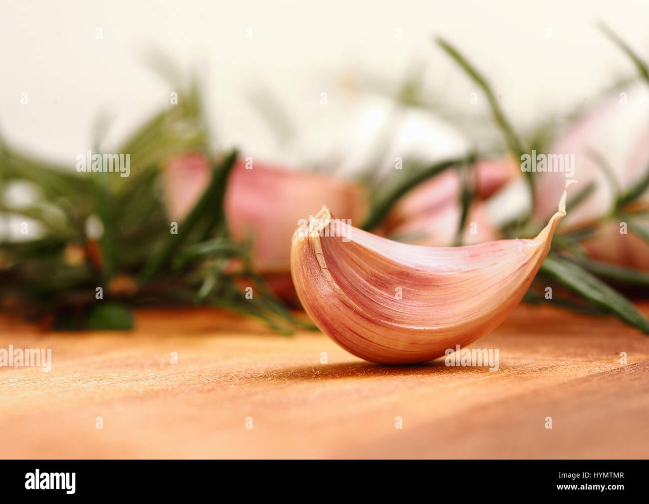 Close up garlic clove with fresh rosemary in background Stock Photo - Alamy