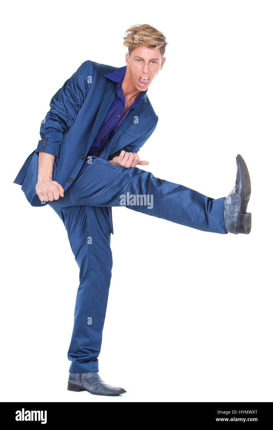Full length portrait of a young man kicking leg up on isolated white background Stock Photo