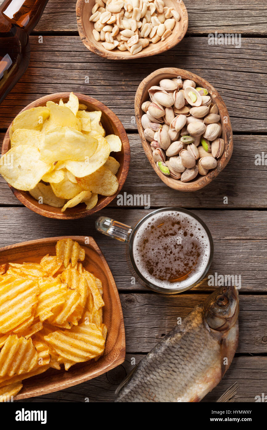 Lager beer mug and snacks on wooden table. Nuts, chips and dry fish