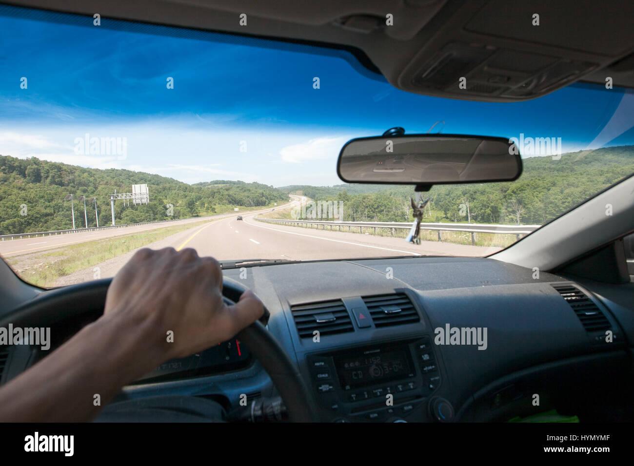 A driver grips the steering wheel as he travels along an open, curved highway. Stock Photo